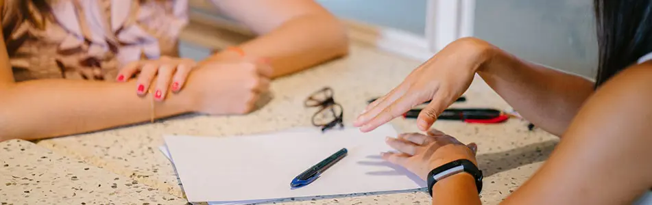 two people's hands next to a piece of paper